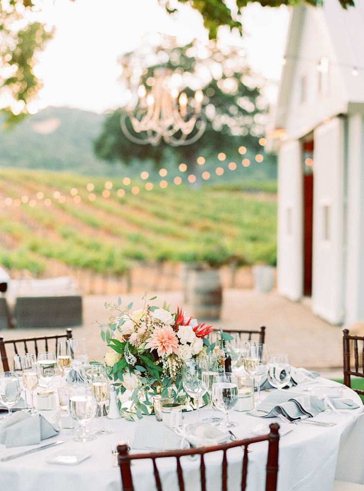 A lovely vineyard venue setting with tabletops by Adornments Flowers.