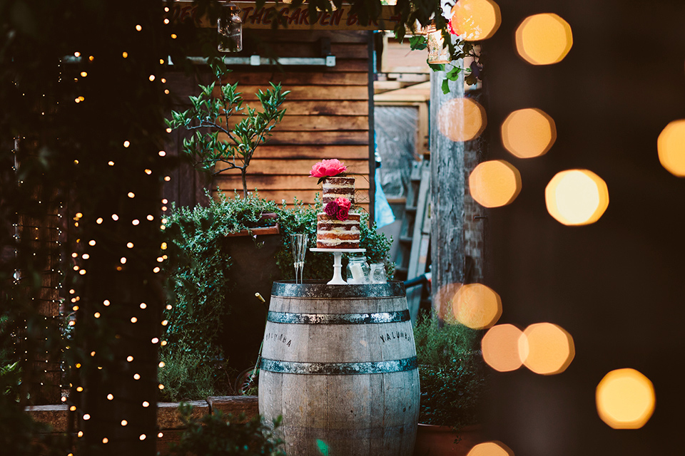 Naked cake displayed on a rustic wine barrel.