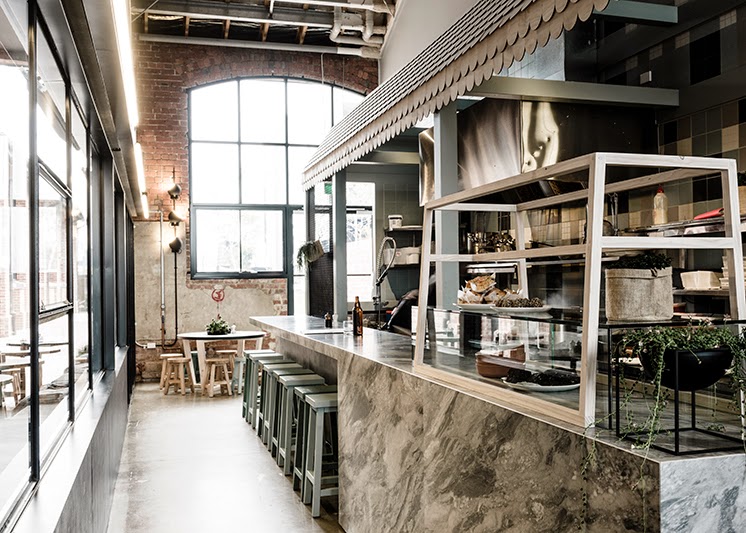 Health-conscious cafe making paleo brunch dishes and salad boxes in an airy, warehouse-style space.