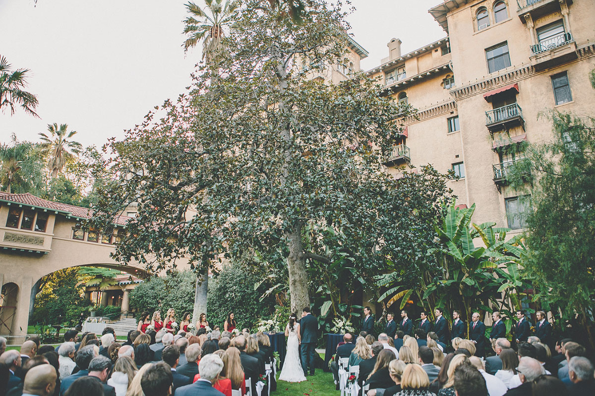 Outdoor ceremony in front of the large tree on the lawn.
