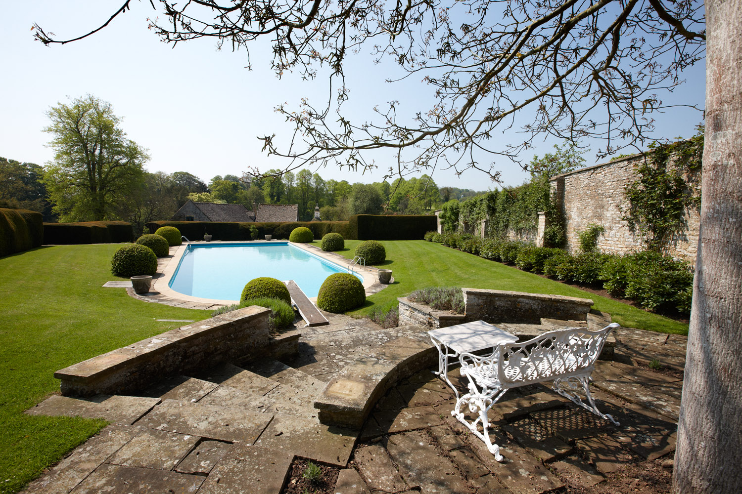 At the back of the house is a wall enclosed triangular pool garden, with ornate hedges and views of the dovecot and stables.