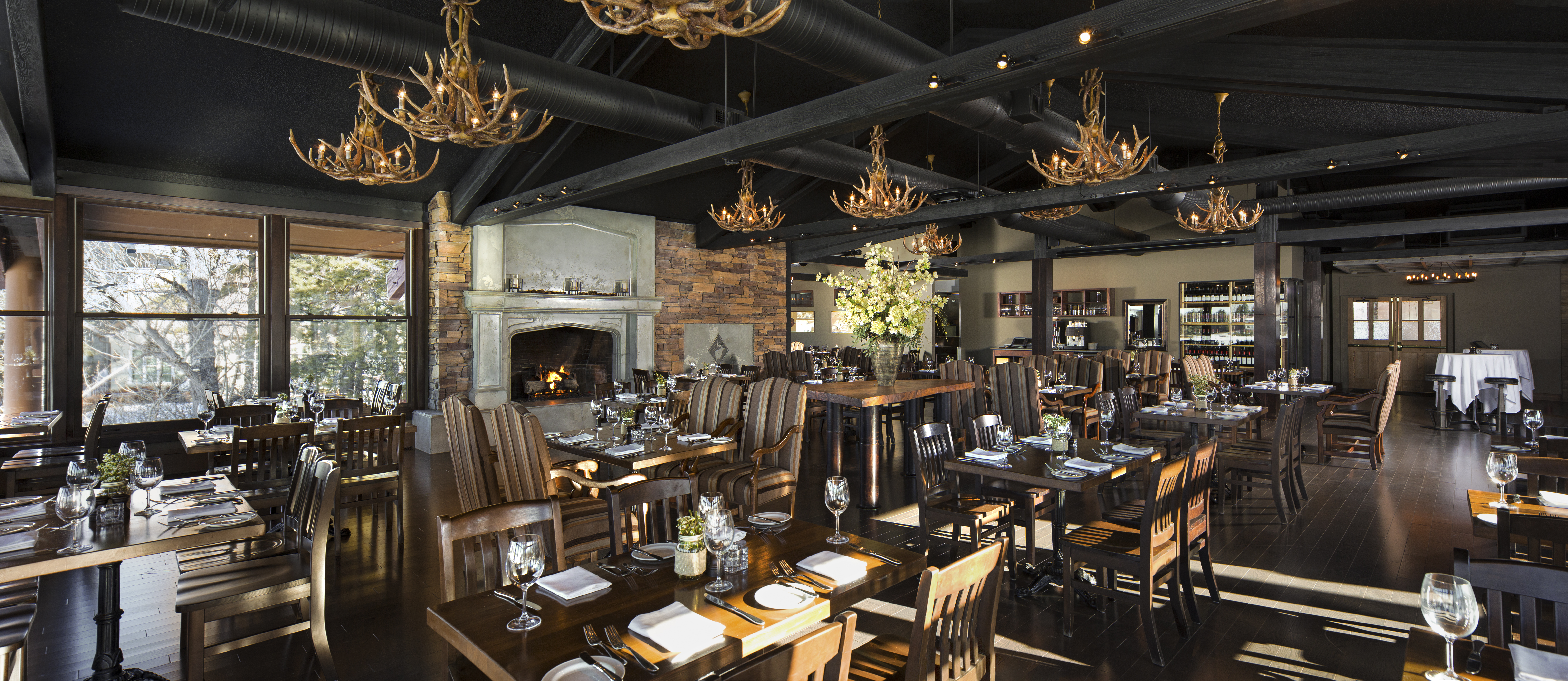 The Bonavista Dining Room offers a large stone fireplace, ornate antler chandeliers and floor to ceiling windows overlooking the lake.